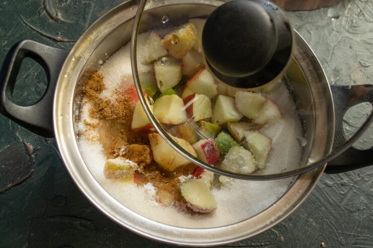 Step 6: Partially covering the pot to help dissolve the sugar. A saucepan with fruit jam mixture, partially covered with a lid.