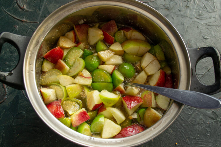Step 7: Simmering the fruit to soften it. The apple and physalis mixture simmering in a pot with the lid on.