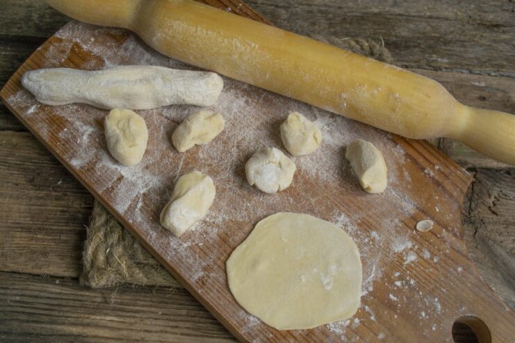 Use a rolling pin to create thin circles of dough for the vareniki filling. Small, thin, round pieces of dough rolled out on a floured surface.