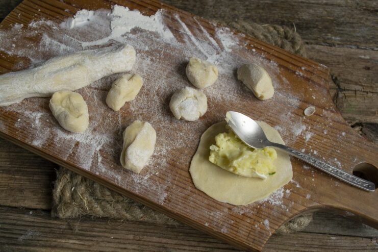 Assembling the vareniki: Placing the filling onto the dough circles. A round piece of dough with a spoonful of potato filling in the center.