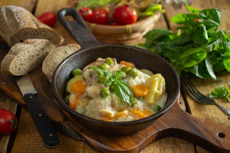 A plate of boiled chicken stewed with vegetables, garnished with fresh herbs.