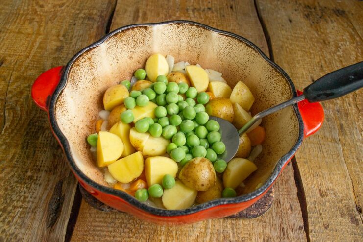 Step 5: Adding peas and water, then simmering covered for 20 minutes. Green peas being added to the pot with potatoes, carrots, and onions.