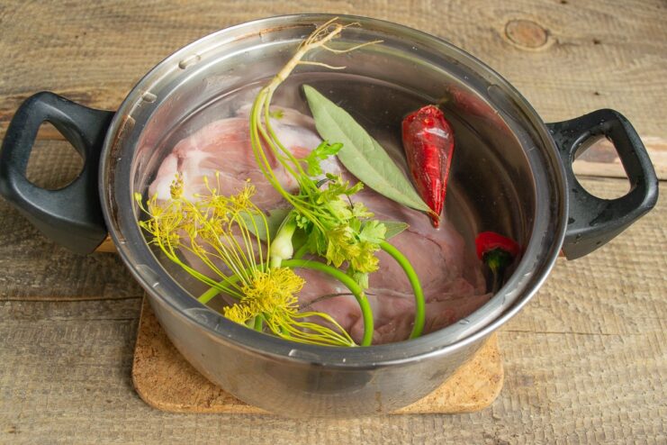 Flavoring the broth while the meat cooks Spices, herbs, and chili being added to the pot with meat and water.