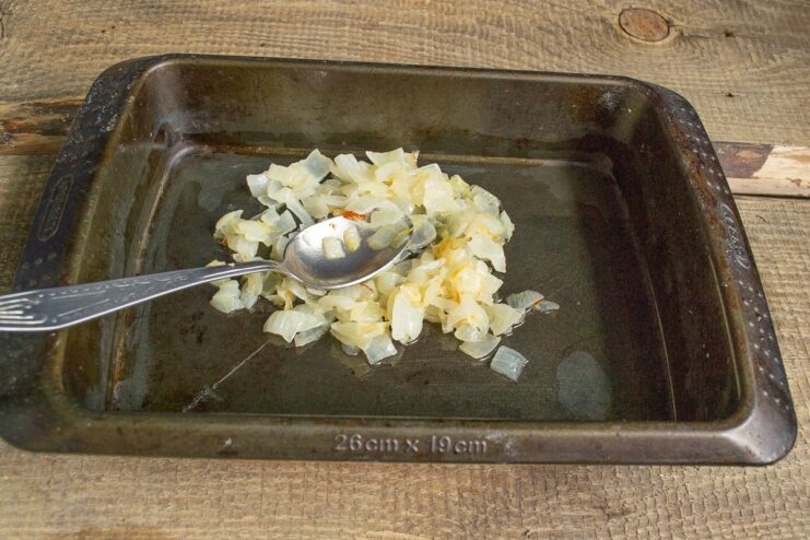 Creating the flavorful base with sautéed onions Sautéed chopped onions spread on the bottom of a glass baking dish.