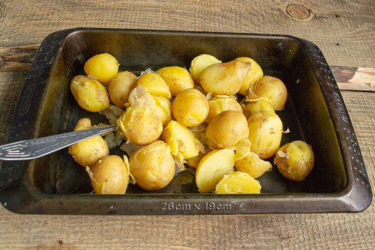Layering the boiled potatoes over the onions Boiled new potatoes being added to the baking dish with sautéed onions.