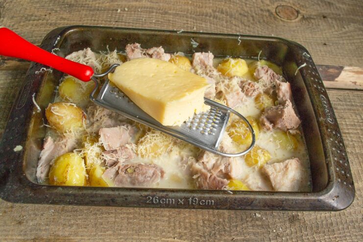 Adding a generous layer of cheese for a golden crust Grating hard cheese over the meat and potato casserole.