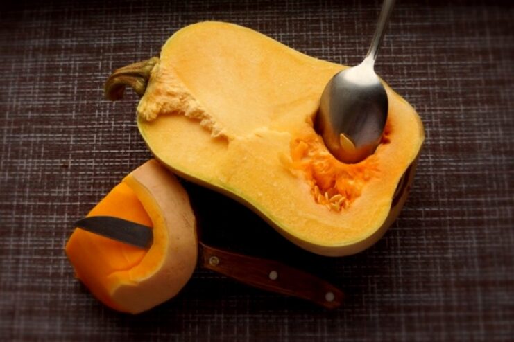 Step-by-step: How to prepare pumpkin for lasagna A pumpkin cut in half with seeds being removed and the tough outer skin being peeled.