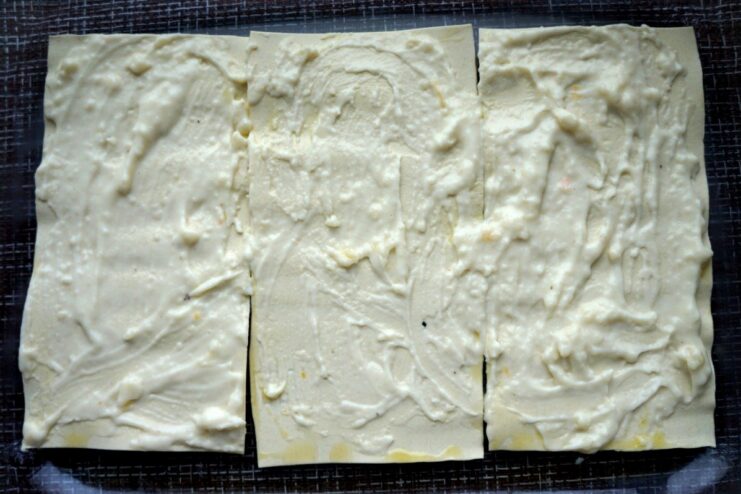 Layering the lasagna with creamy Béchamel sauce A layer of lasagna sheets being generously covered with creamy white Béchamel sauce.