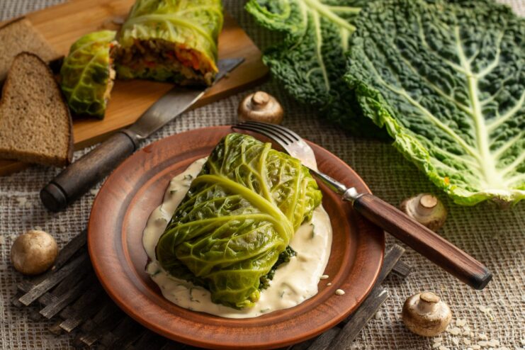 A plate of vegetarian steamed savoy cabbage rolls with mushrooms, garnished for serving.