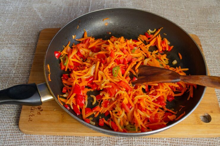 Cooking the vegetable mixture with bell peppers for the golubtsy filling Diced bell peppers being added to a pan of sautéing vegetables.