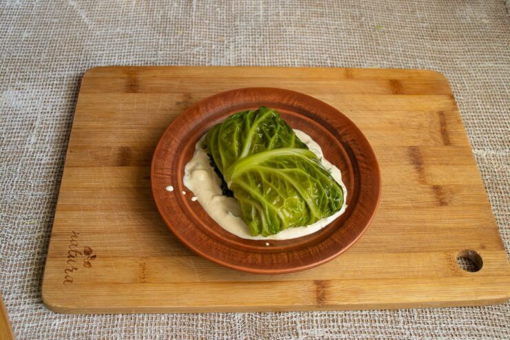 Serving the freshly steamed vegetarian golubtsy with a delicious sauce Finished vegetarian steamed cabbage rolls on a plate, drizzled with sauce.