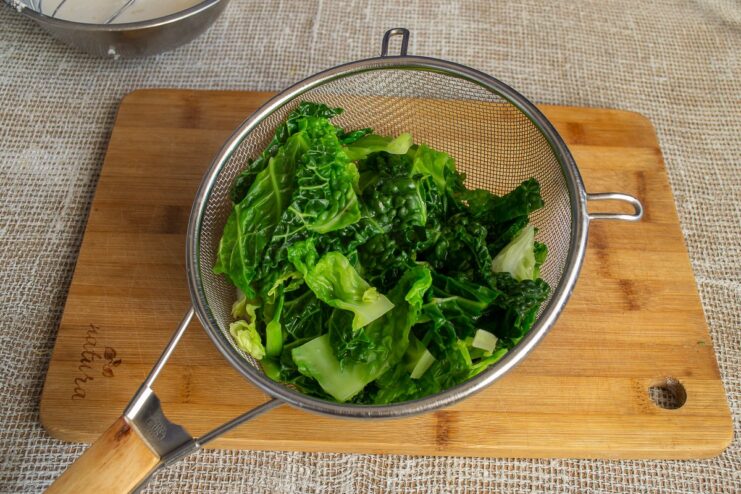Quickly blanching the cabbage helps retain its vibrant green color and tender texture. Sliced Savoy cabbage being blanched in a pot of boiling water.