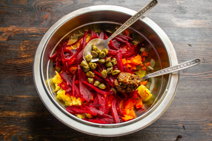 Adding a spoonful of spicy adjika paste for a flavorful kick. A teaspoon of red spicy adjika paste being added to the salad.