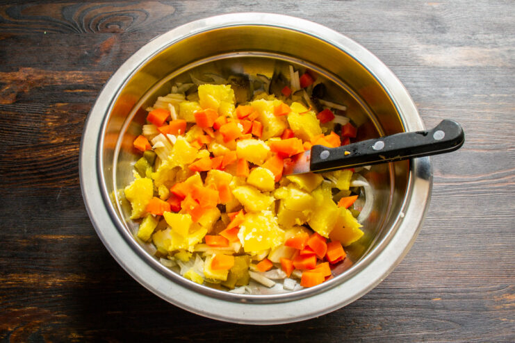 Adding finely chopped baked carrots to the salad. Finely chopped baked carrots being added to the salad bowl.