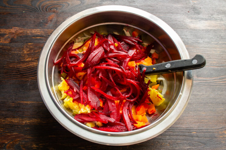 Adding julienned baked beets to the salad for its signature color. Julienned baked beets being added to the bowl with other salad ingredients.