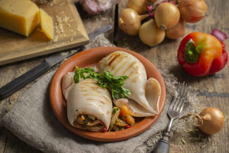 A plate of grilled squid stuffed with vegetables and cheese, garnished with herbs.