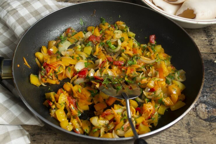 Cooking the Full Vegetable Filling with Carrots, Tomatoes, and Herbs A colorful mix of sautéed vegetables, including carrots and tomatoes, in a pan.