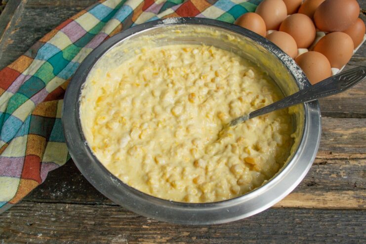 Adding Wet Ingredients to the Corn Pie Batter Adding eggs and melted butter to the corn pie batter in a large bowl.