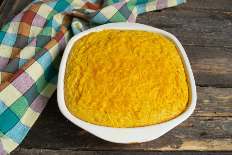 Freshly Baked Cheddar Corn Pie A golden-brown, freshly baked cheddar corn pie in a ceramic dish, ready to be served.