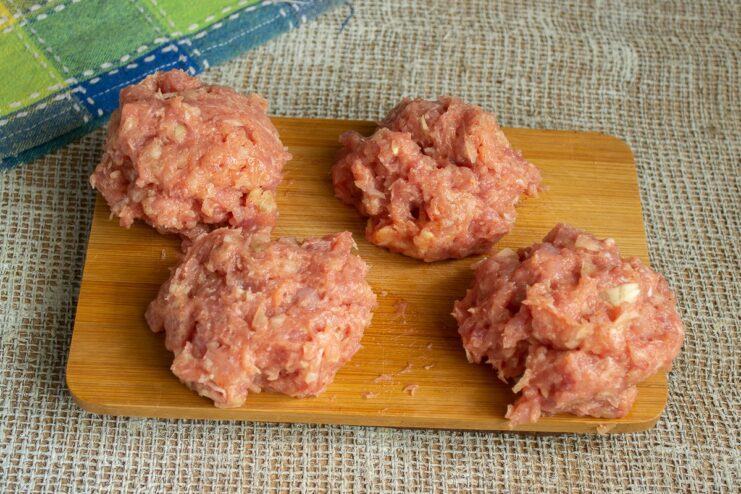 Portioning the Ground Pork for Four Scotch Eggs Four equal portions of seasoned ground pork on a cutting board.