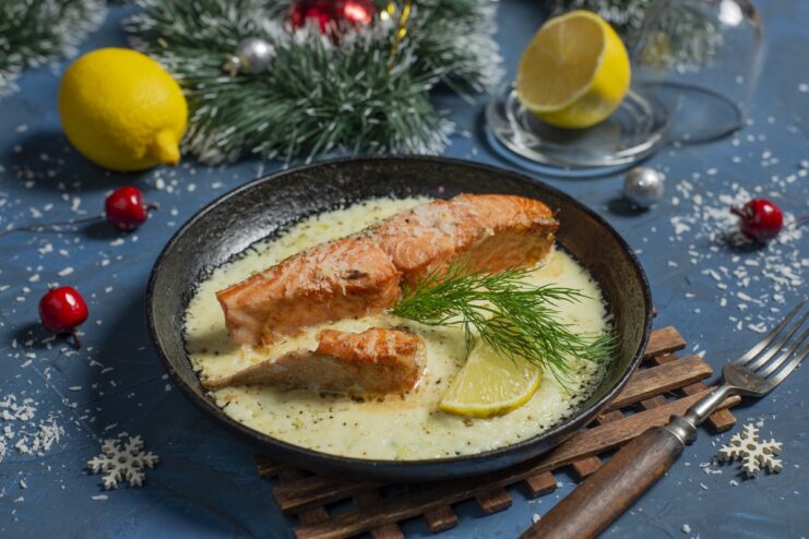 A serving of baked trout in a creamy coconut sauce, garnished with dill and a lemon slice.