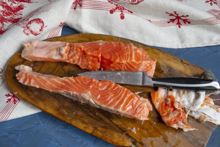 Preparing the trout fillets by removing skin and bones. Two large, prepared trout fillets ready for marinating.