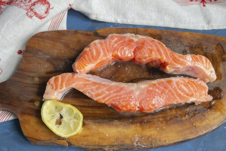 Marinating the trout with lemon juice and salt enhances its flavor. Trout fillets being patted dry with a paper towel after marinating.