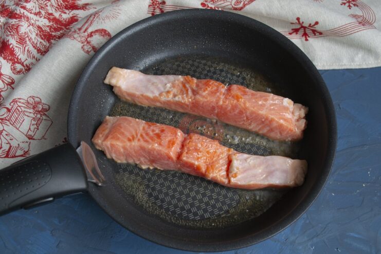 Quickly searing the trout creates a beautiful crust before baking. Trout fillets being seared in a hot frying pan.