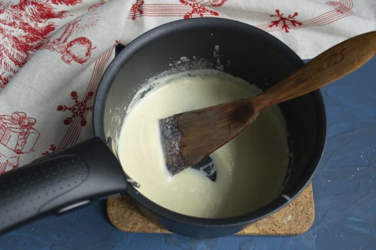 Adding fresh lemon juice to brighten up the creamy sauce. Squeezing fresh lemon juice through a sieve into the cream sauce.