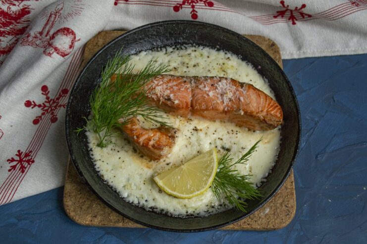Serve this elegant baked trout immediately for the best experience. The final dish of baked trout in creamy coconut sauce served in a skillet.