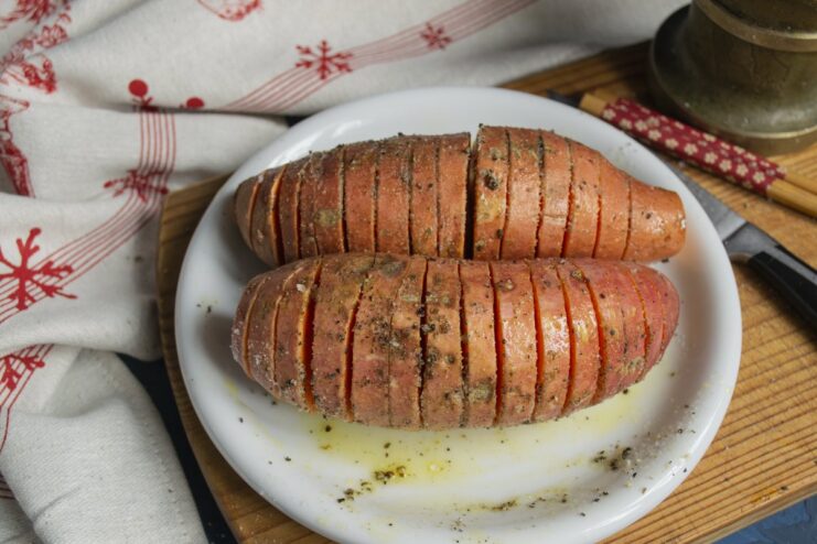 Adding Salt and Pepper to Sweet Potatoes Seasoning the sliced sweet potato with coarse salt and freshly ground black pepper.