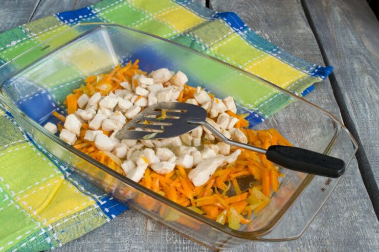 Adding Pan-Fried Chicken to the Vegetable Base Pan-fried chicken pieces being added on top of the sautéed vegetables in a baking dish.