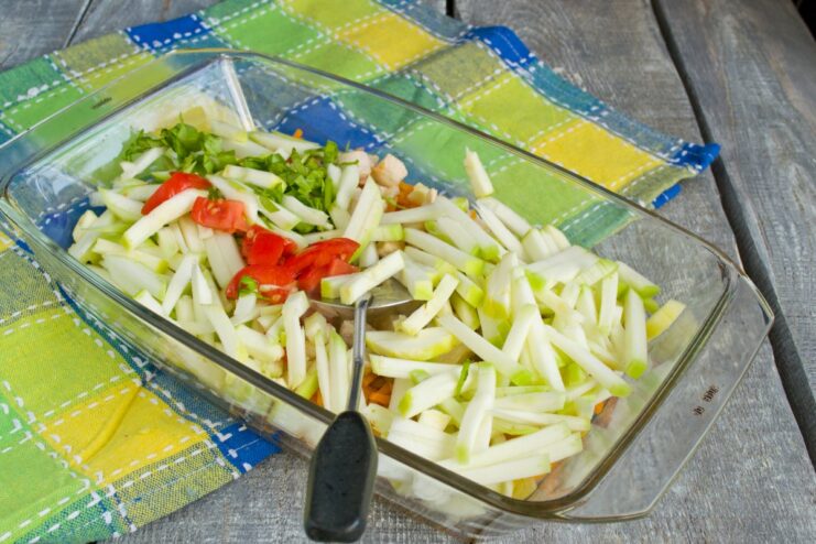 Mixing in Fresh Zucchini and Tomato Chopped fresh zucchini and tomato being added to the chicken and vegetable mixture in the dish.