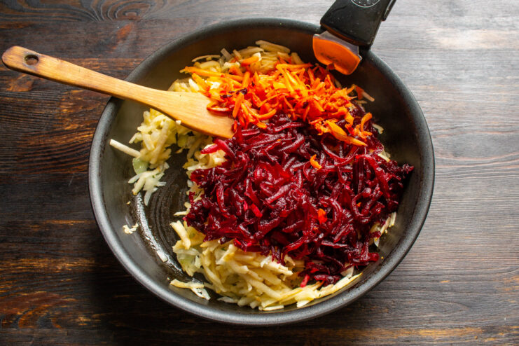 Preparing the main vegetables: grating carrots and beets for the dressing. A pile of coarsely grated carrots and beets ready to be cooked.