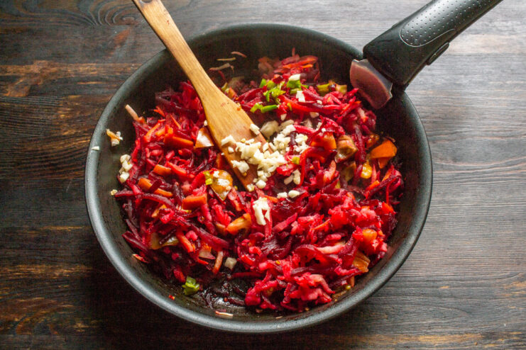 Adding aromatics: minced garlic and chili pepper for a spicy kick. Minced garlic and chili pepper being added to the vegetable mixture in the pan.