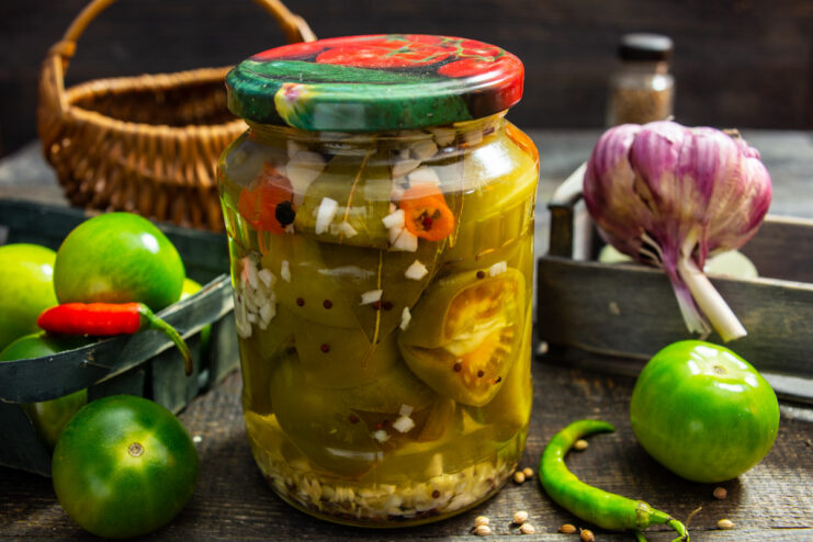 A jar of homemade pickled green tomatoes with horseradish and garlic, ready for winter storage.