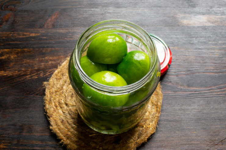 Packing Jars with Green Tomatoes - Cut Side Down for Best Results Glass jars being filled with halved green tomatoes, arranged neatly with the cut side down.