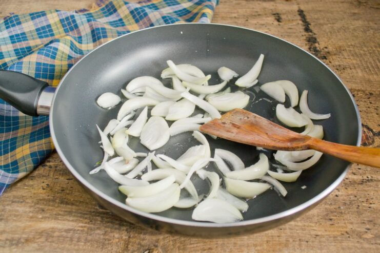 Sautéing Onions to Build a Flavorful Base Sliced onions being sautéed in a hot skillet until golden.