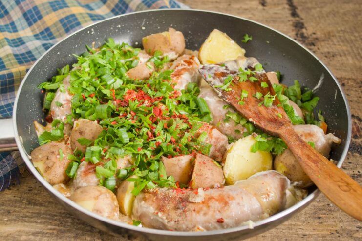 Garnishing with Fresh Herbs and Paprika for a Final Touch The finished dish in the skillet, being garnished with chopped fresh herbs and paprika.