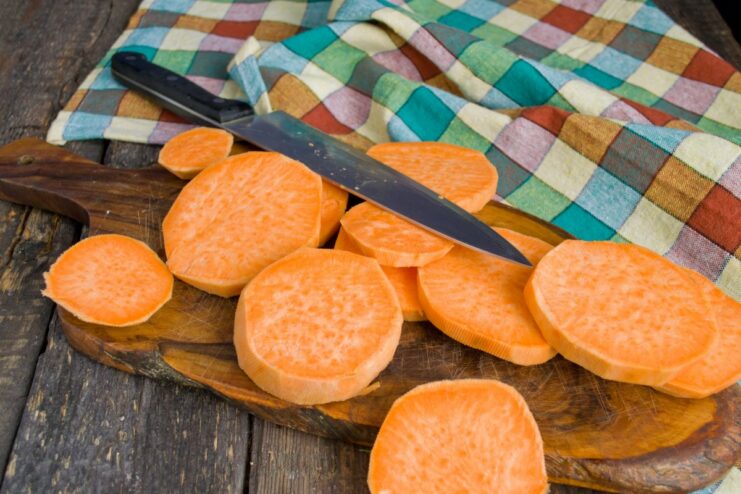 How to Slice Sweet Potato for Frying Peeled sweet potato being cut into thick, round slices on a cutting board.