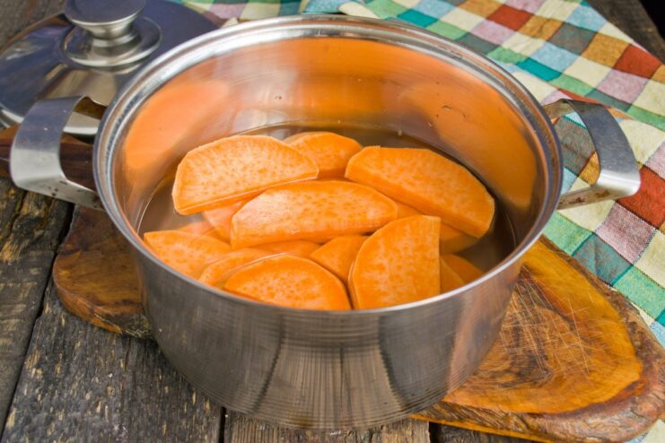 Parboiling Sweet Potato Slices Before Frying Sweet potato slices in a saucepan with a small amount of boiling water to parboil them.