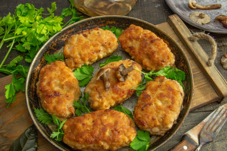 A plate of golden-brown breaded meat zrazy, stuffed with mushrooms and onions, garnished with fresh parsley.