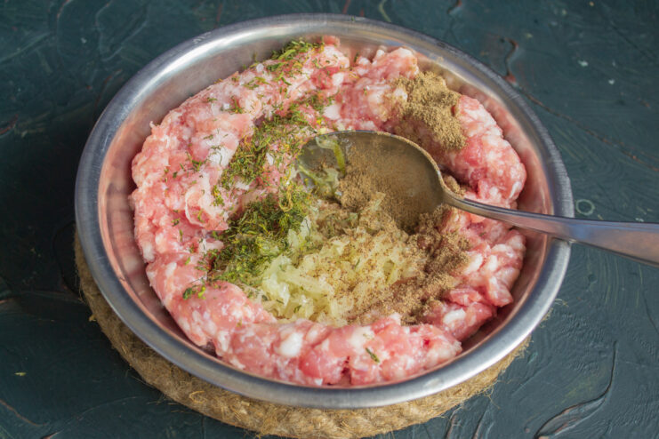 Mixing the Minced Meat for Juicy Zrazy A hand mixing minced meat with seasonings in a glass bowl to prepare it for the zrazy.