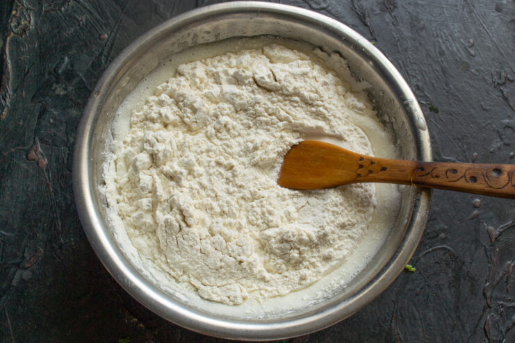 Adding dry ingredients to the wet mixture Flour and baking powder being added to the bowl of wet cake batter ingredients.