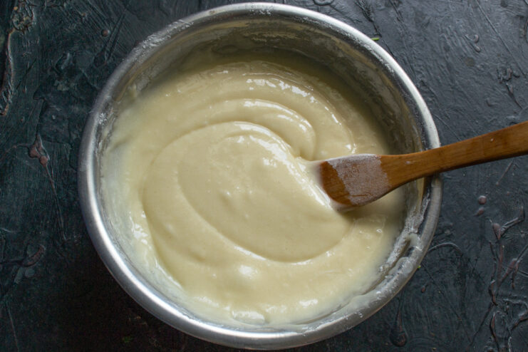 The final consistency of the upside-down cake batter A thick, smooth, pale yellow cake batter in a glass bowl with a spatula.