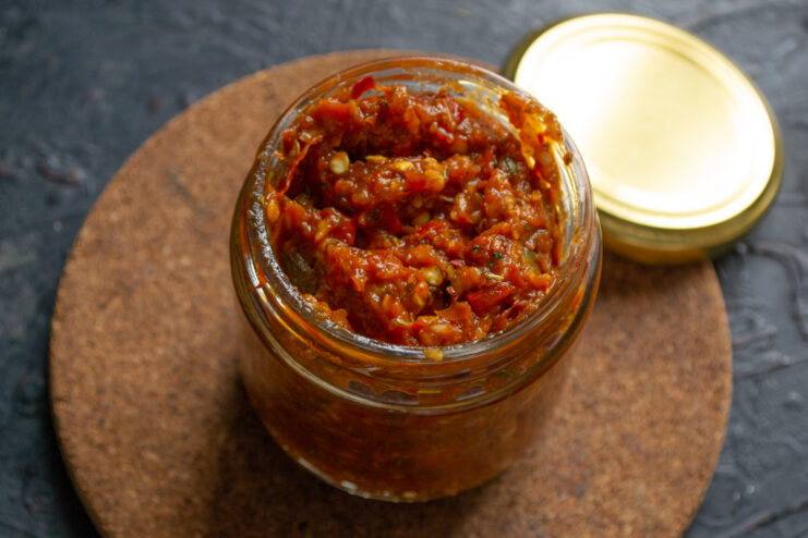 Storing the Finished Adjika in a Jar A spoon transferring the finished red chili adjika paste into a clean glass jar.