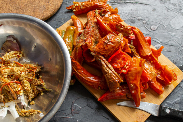Step 3: Deseeding the Rehydrated Chili Peppers A hand wearing a glove is shown deseeding a rehydrated red chili pepper.