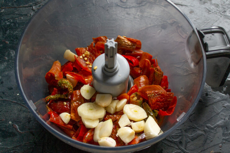 Using a Blender to Make Adjika Paste Deseeded chili peppers and garlic cloves in a blender bowl, ready to be processed.