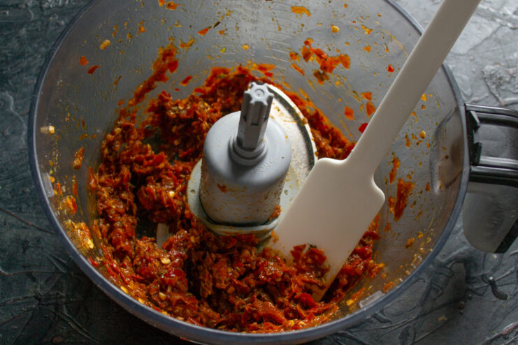 Blending the Ingredients into a Thick Paste The process of blending chili peppers, garlic, and herbs into a thick red adjika paste.