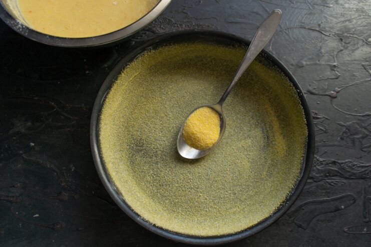 Preparing the baking pan by greasing it with butter for a non-stick finish. A round baking pan being generously greased with softened butter.